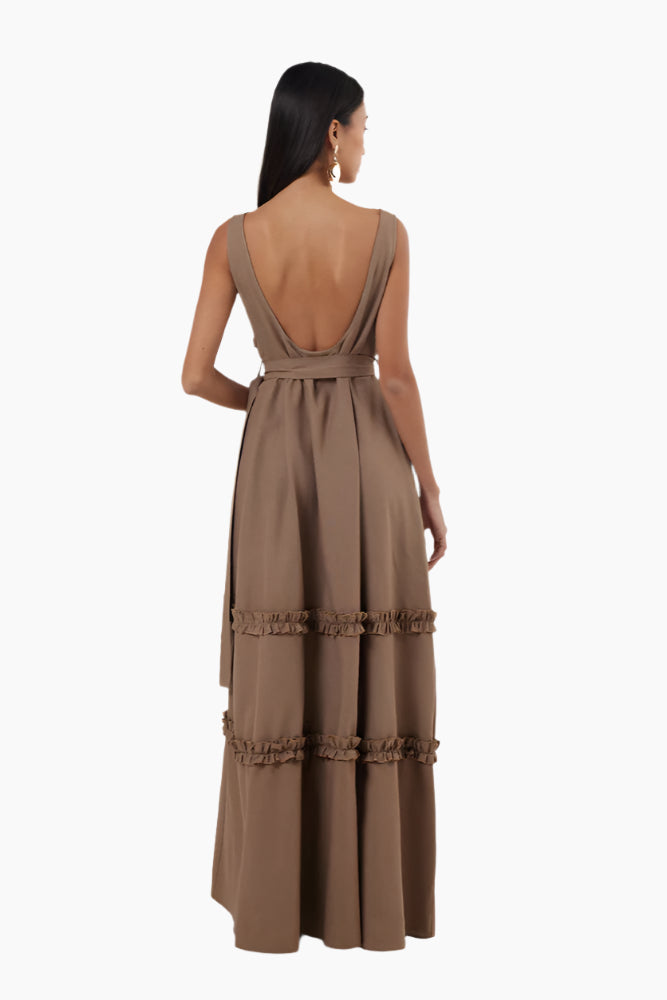 Woman wearing a brown dress with a belt . Floor-length dress with double ruffles, deep rounded neckline, belt, and a slit.