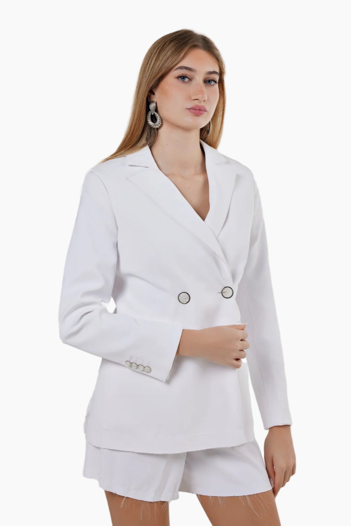 Woman wearing a white blazer and shorts set on a plain background