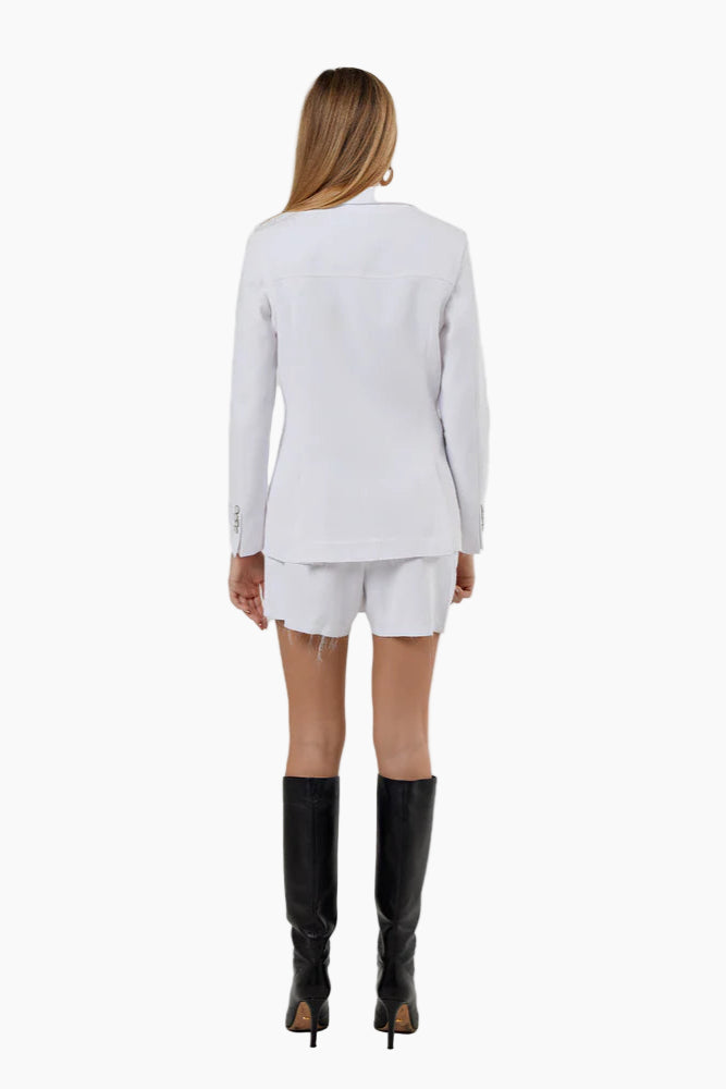 Woman wearing a white outfit with black knee-high boots on a white background