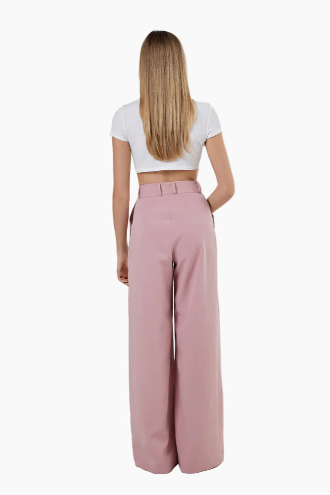 Person wearing a white crop top and pink high-waisted pants on a white background