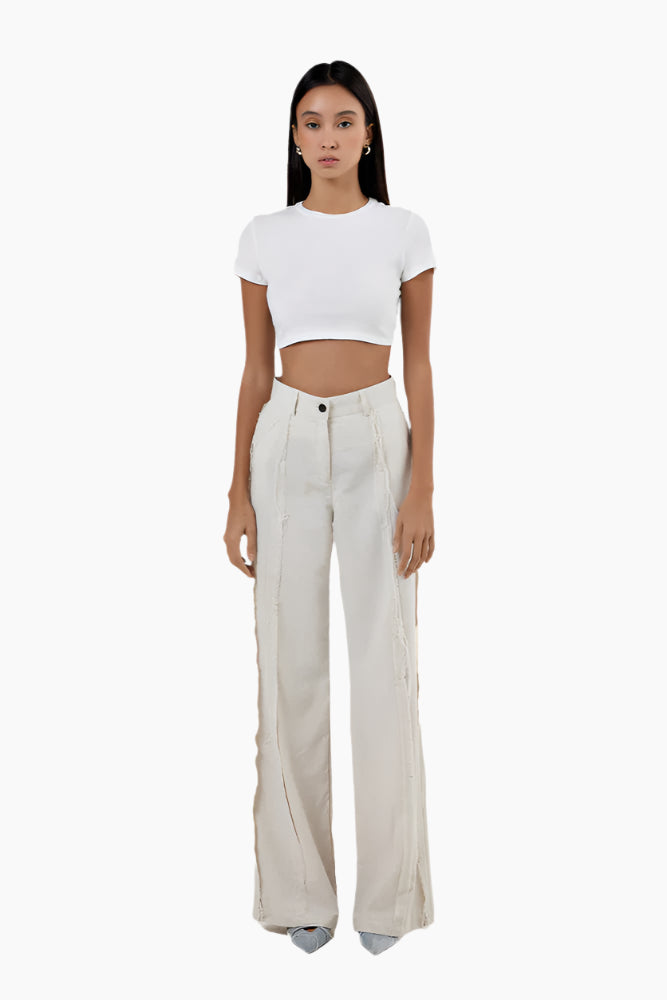 Woman wearing a white crop top and beige wide-leg pants