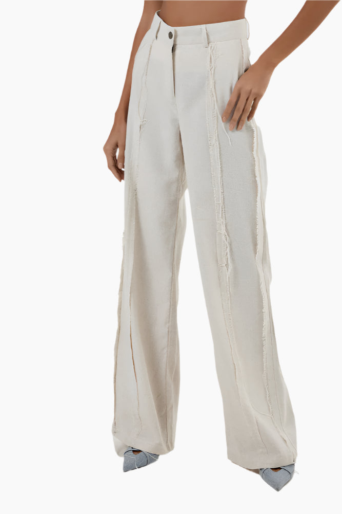 High-waisted flared pants with a cut on each leg, unfinished seams to the outside, front zip fly, and button fastening.