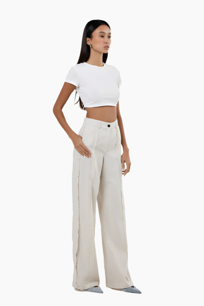 High-waisted flared pants with a cut on each leg, unfinished seams to the outside, front zip fly, and button fastening.