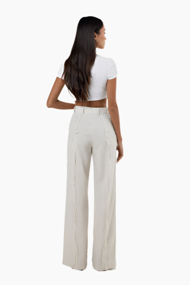 Woman wearing a white crop top and beige high-waisted pants