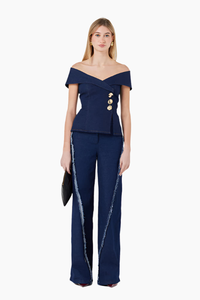 Woman wearing a navy blue off-shoulder top and pants with gold buttons . Off-shoulder double-breasted top with buttoning and topstitching details.