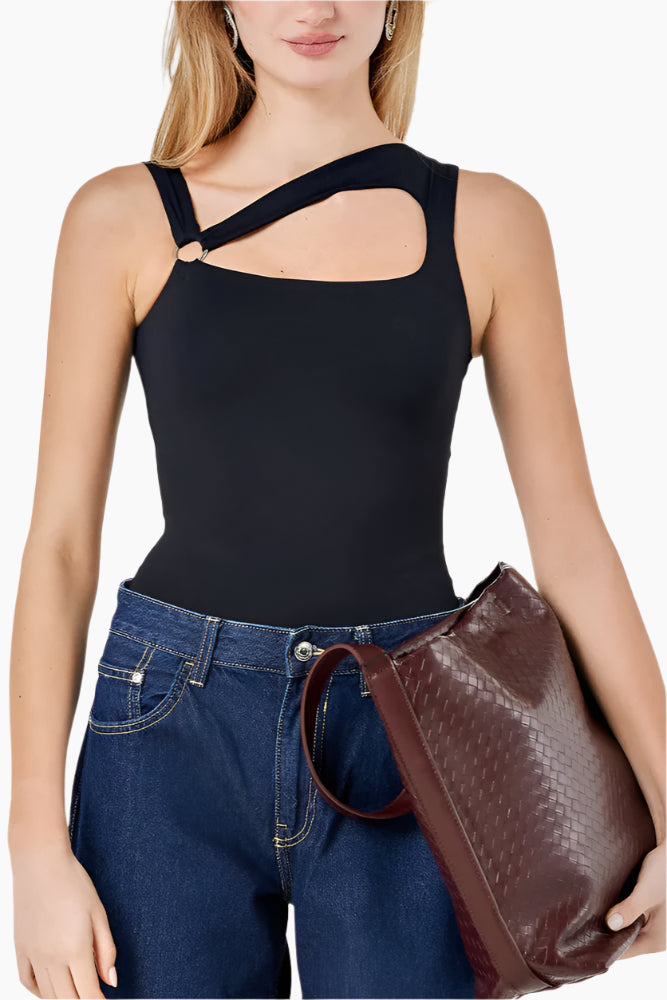 Woman wearing a black sleeveless top and blue jeans, holding a brown leather handbag.