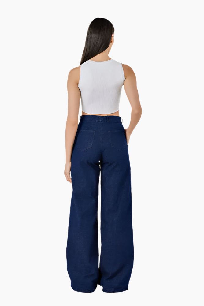 Woman wearing a white sleeveless top and blue high-waisted pants with fringe details . High-waisted flared pants with a cut on each leg, unfinished seams on the outside, front zip fly, and button fastening.