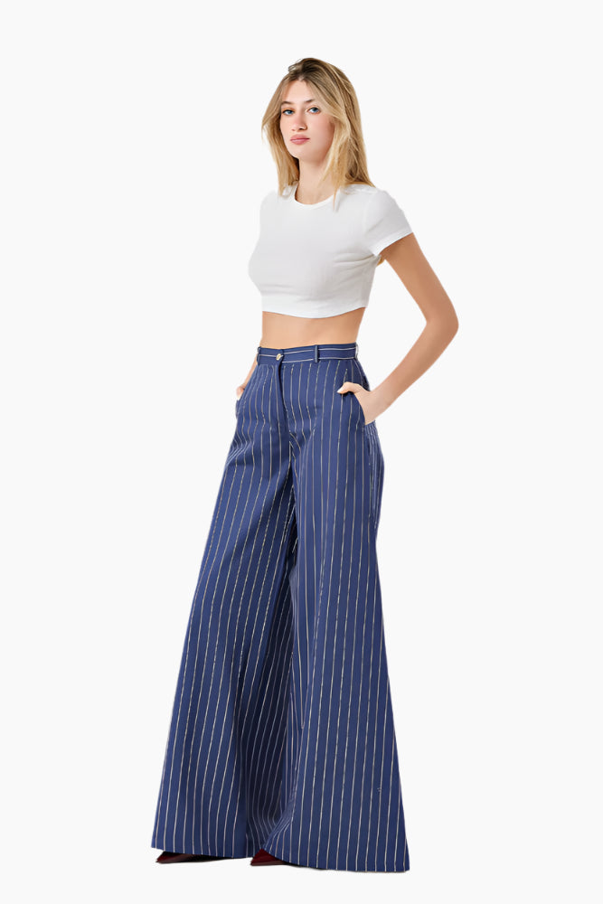 Woman wearing a white crop top and blue striped wide-leg pants. High-waist trousers with a wide-leg design and a front zip fly.