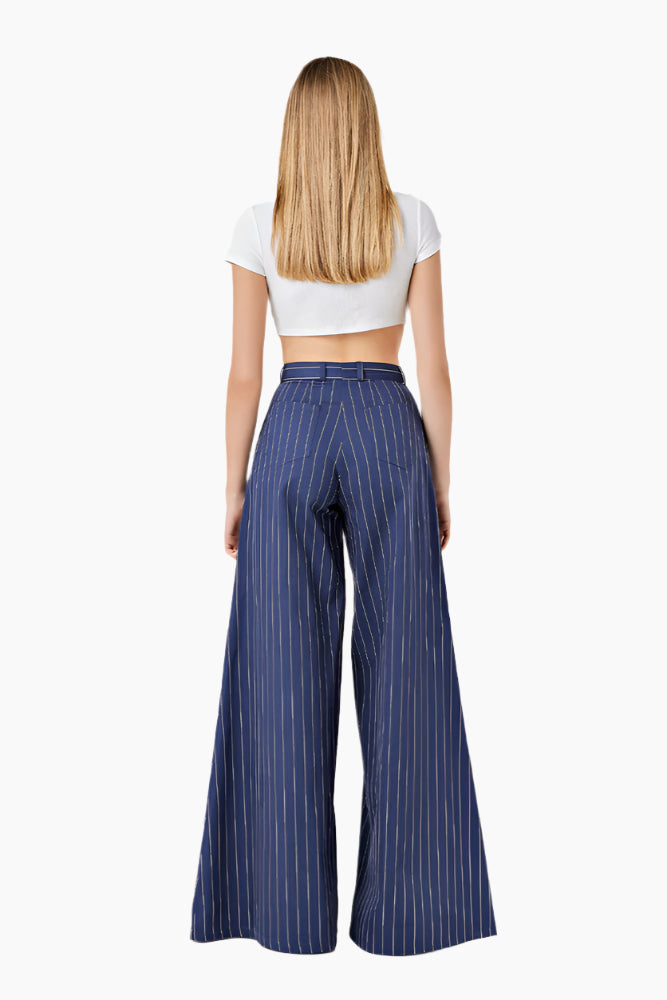 Woman wearing a white crop top and blue striped wide-leg pants. High-waist trousers with a wide-leg design and a front zip fly.