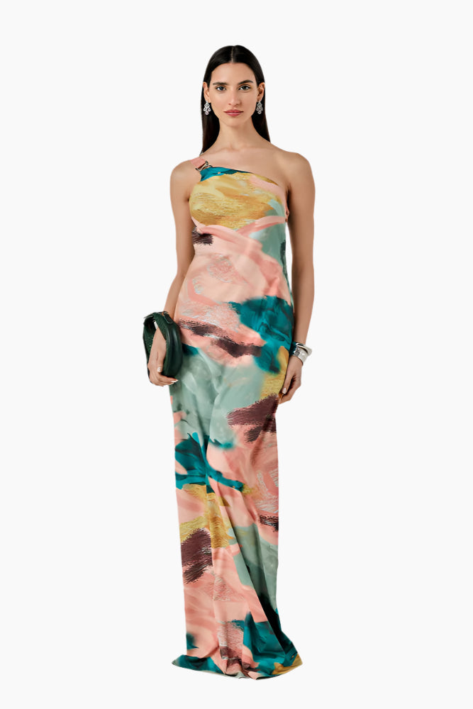 Woman wearing a colorful floral dress. Relaxed-fit asymmetrical one-shoulder dress with a side slit closed by buttons.