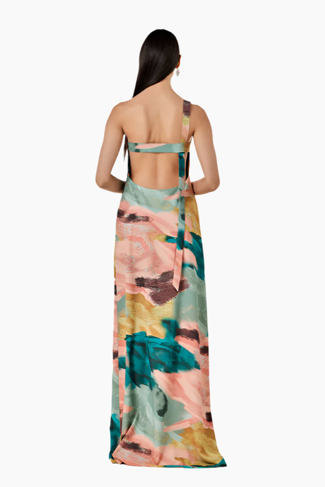 Woman wearing a colorful floral dress. Relaxed-fit asymmetrical one-shoulder dress with a side slit closed by buttons.