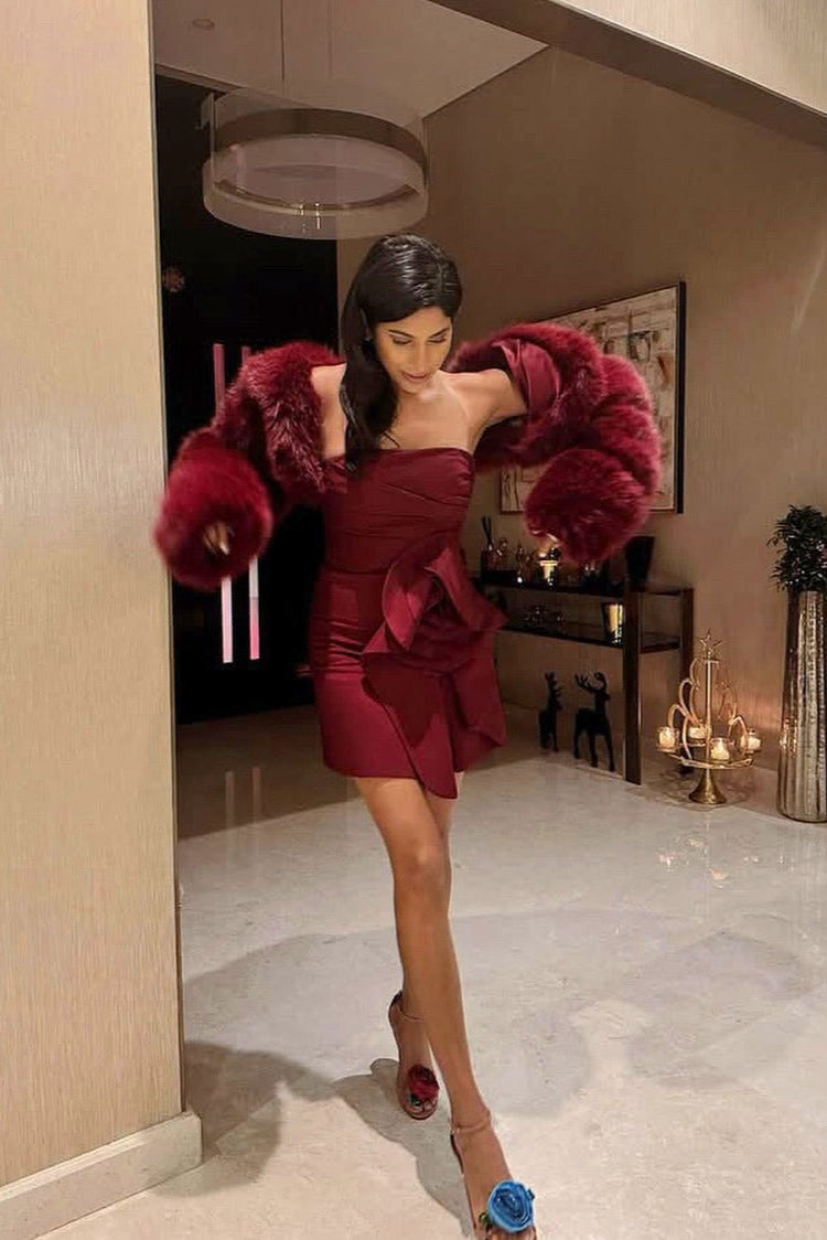 Woman in a red dress with a fur coat standing in a room