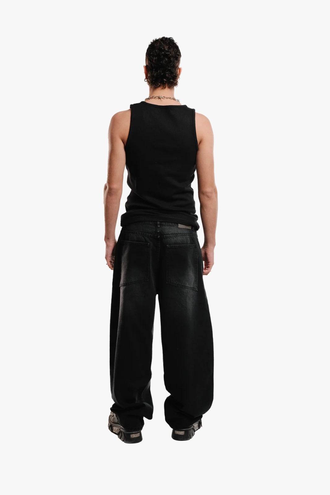 A person standing wearing a black sleeveless top and black pants.