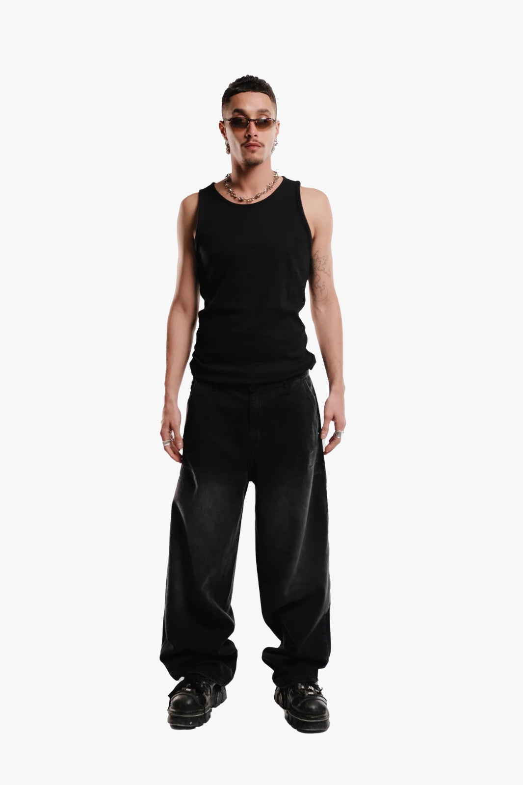 A person standing wearing a black sleeveless top and black pants.