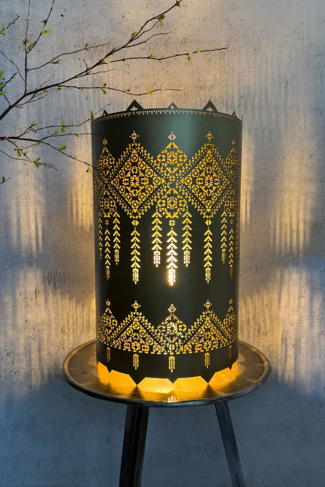 Decorative lamp with geometric pattern on a stand against a textured wall.