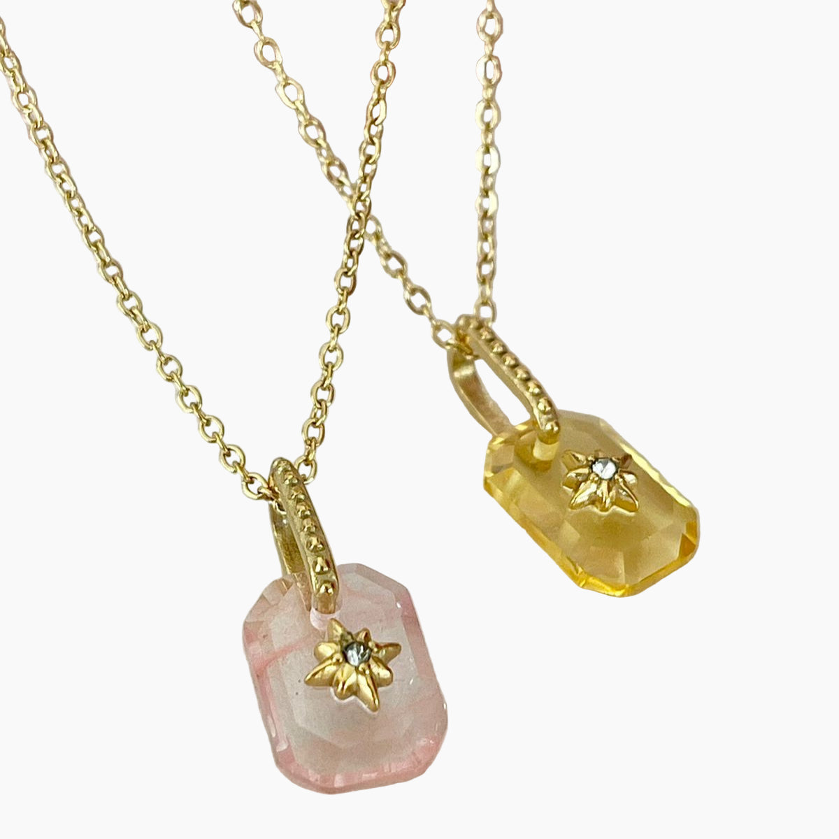 Two gold necklaces with stone pendants on a white background
