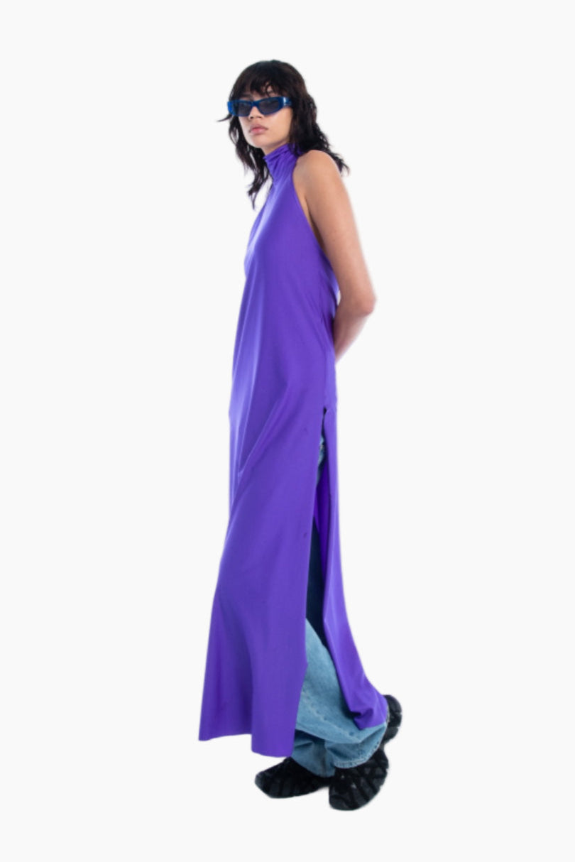 Person wearing a long purple dress with a high slit on a white background