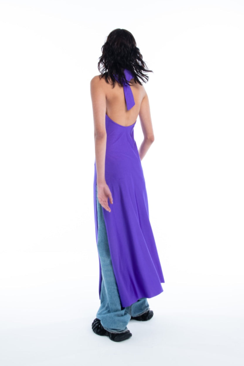 Person wearing a long, open-back purple dress with a blue bottom section on a white background