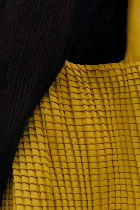 Close-up of textured yellow fabric with a black background