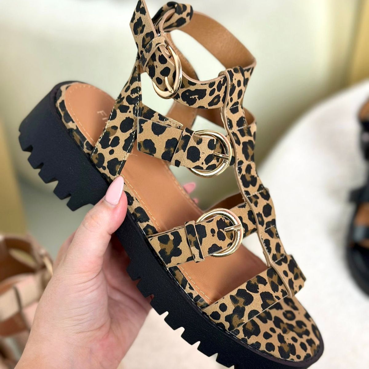 Leopard print sandal with black sole held by a hand