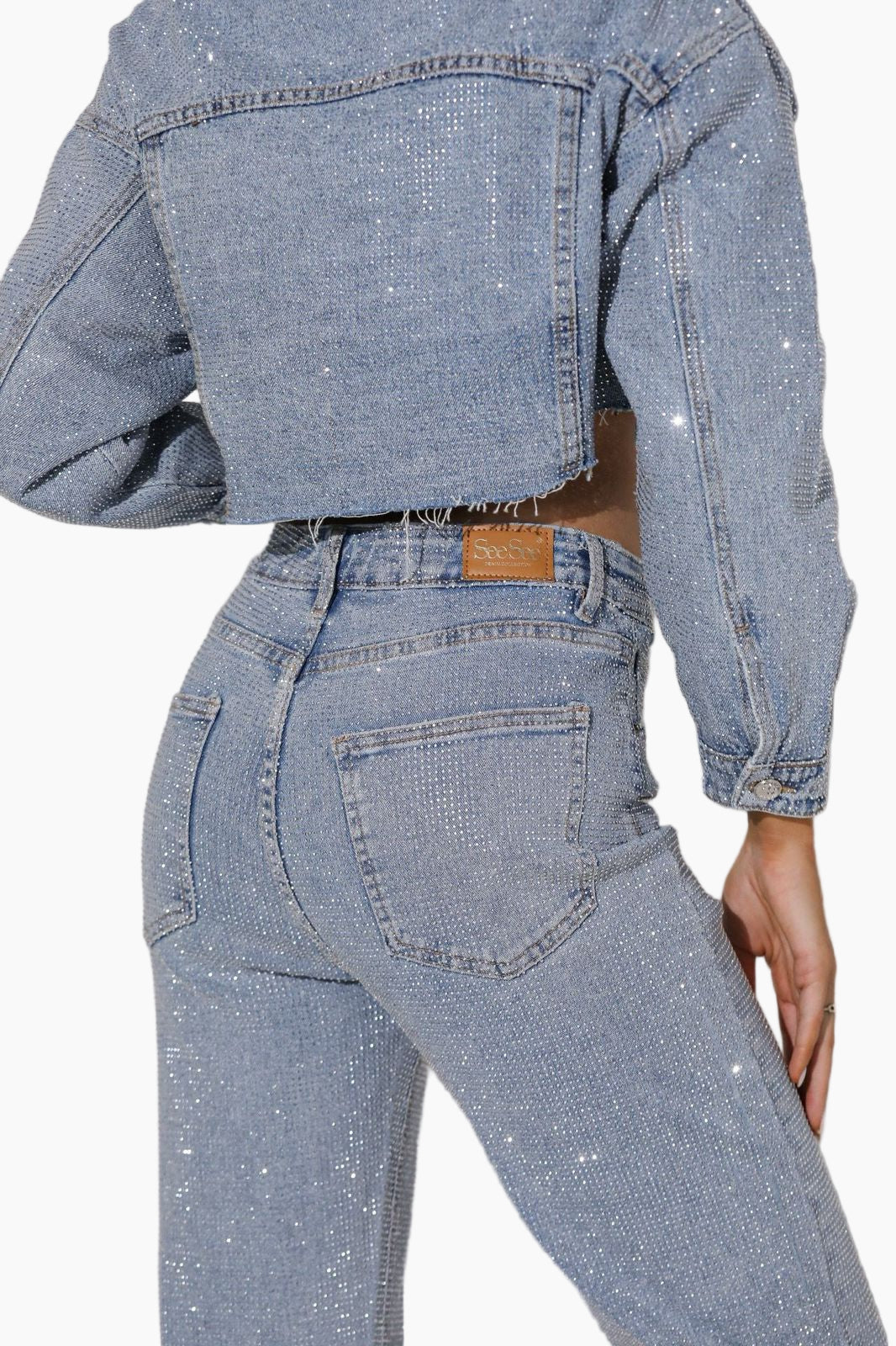 Person wearing a blue denim jacket and jeans on a white background