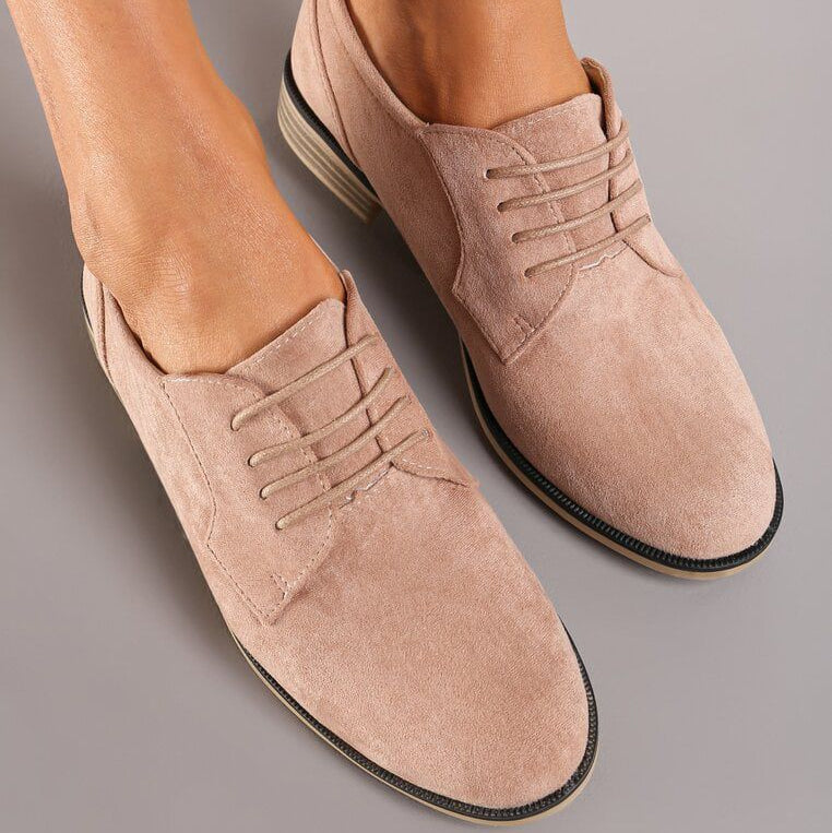 Beige suede shoes worn by a person on a gray background