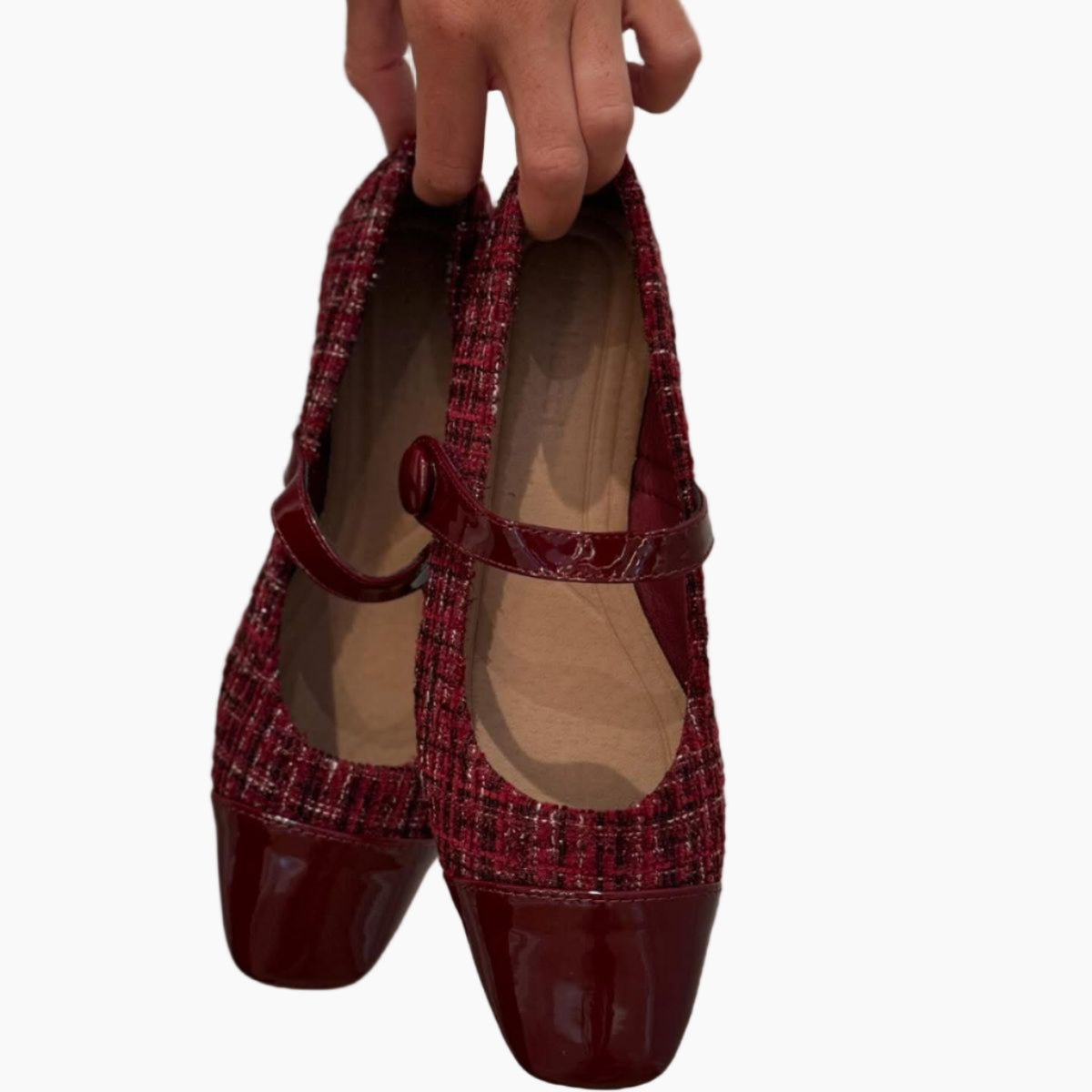 Red tweed shoes with a shiny toe cap held by a hand