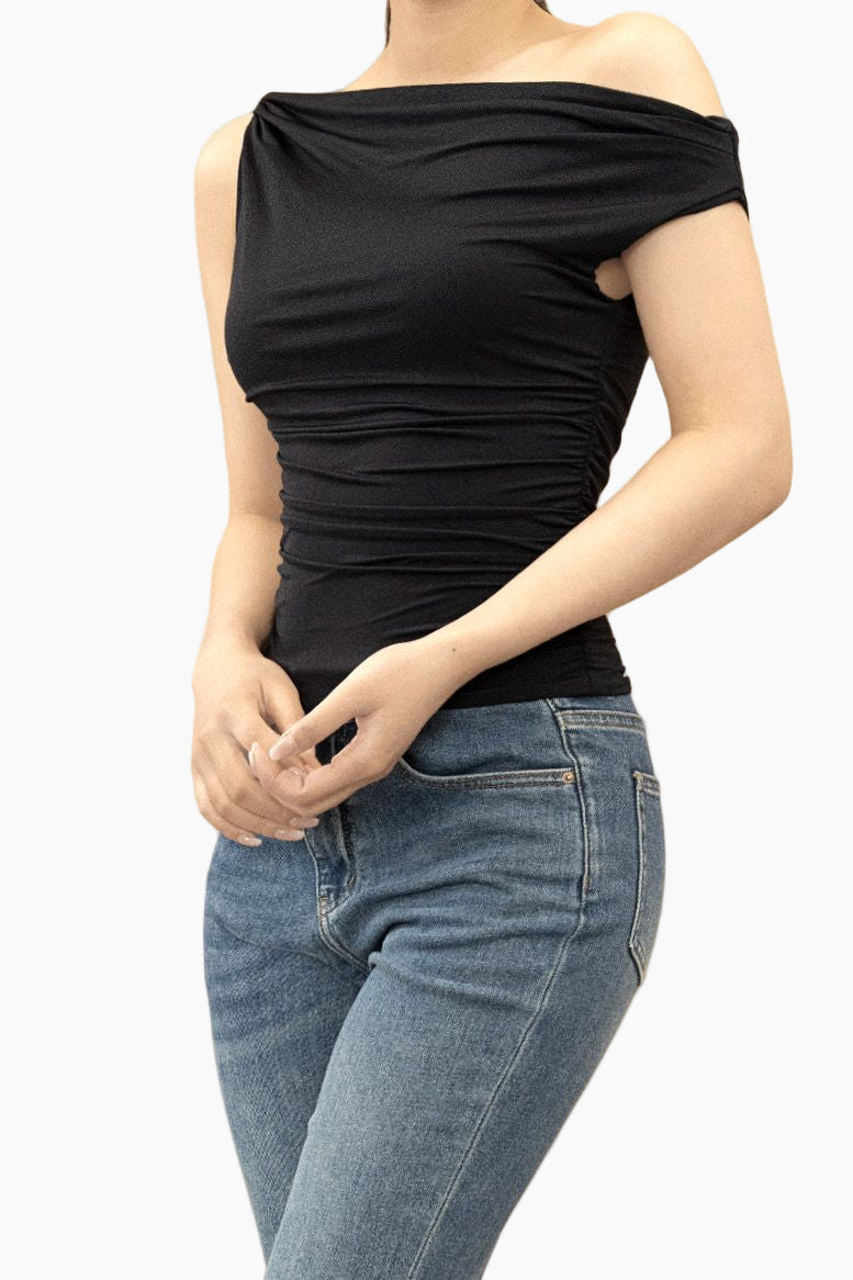 Person wearing a black off-shoulder top and blue jeans