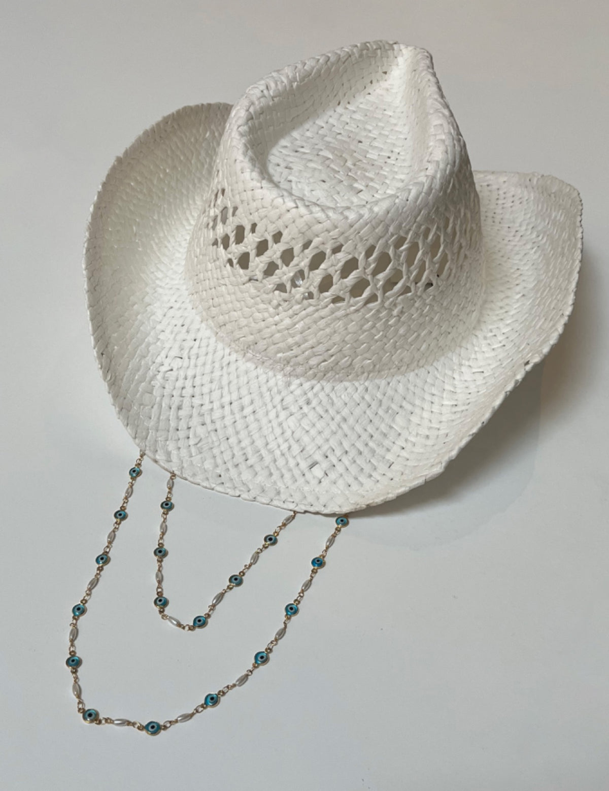 White cowboy hat with a beaded band on a light gray background