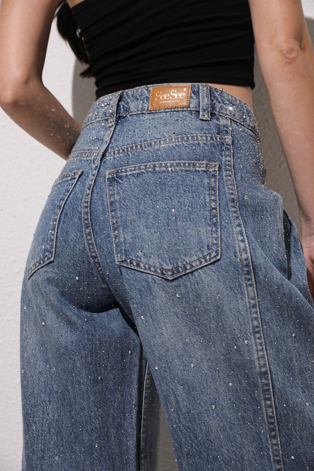 Person wearing blue jeans with a visible brand label