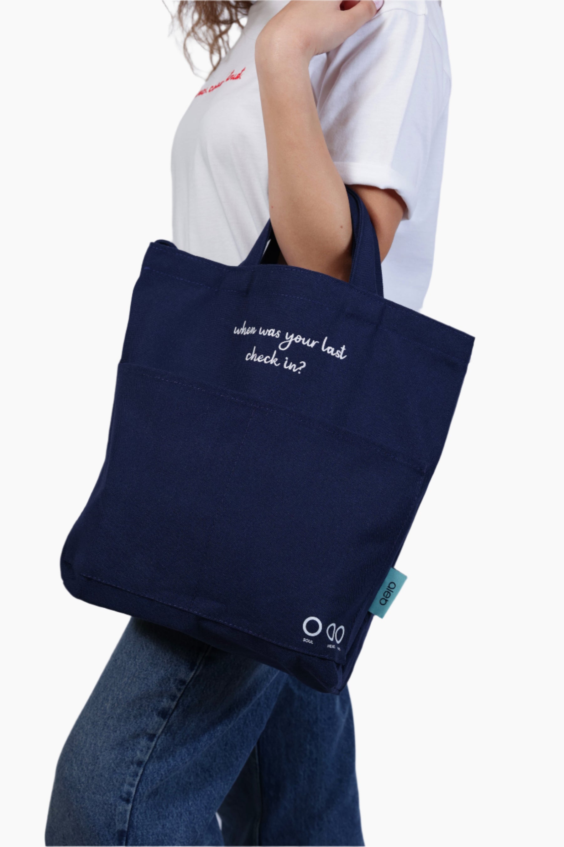 Person wearing a navy blue bag "When was your last check in?" - Unisex Tote Bag