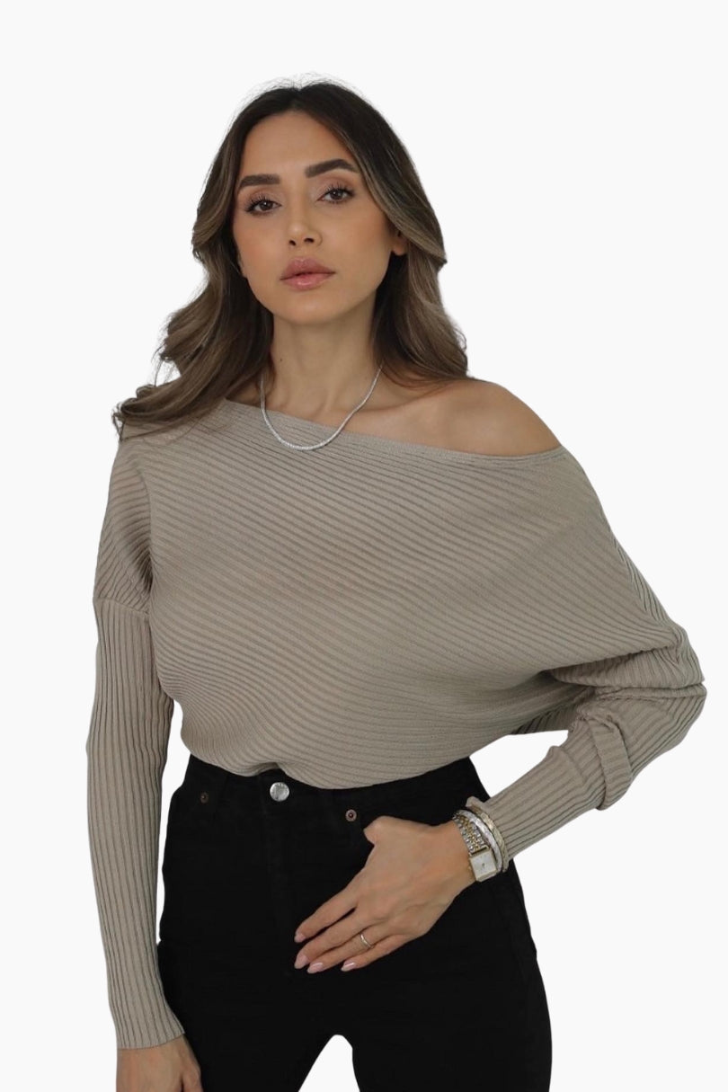 Woman wearing a beige off-shoulder sweater and black pants