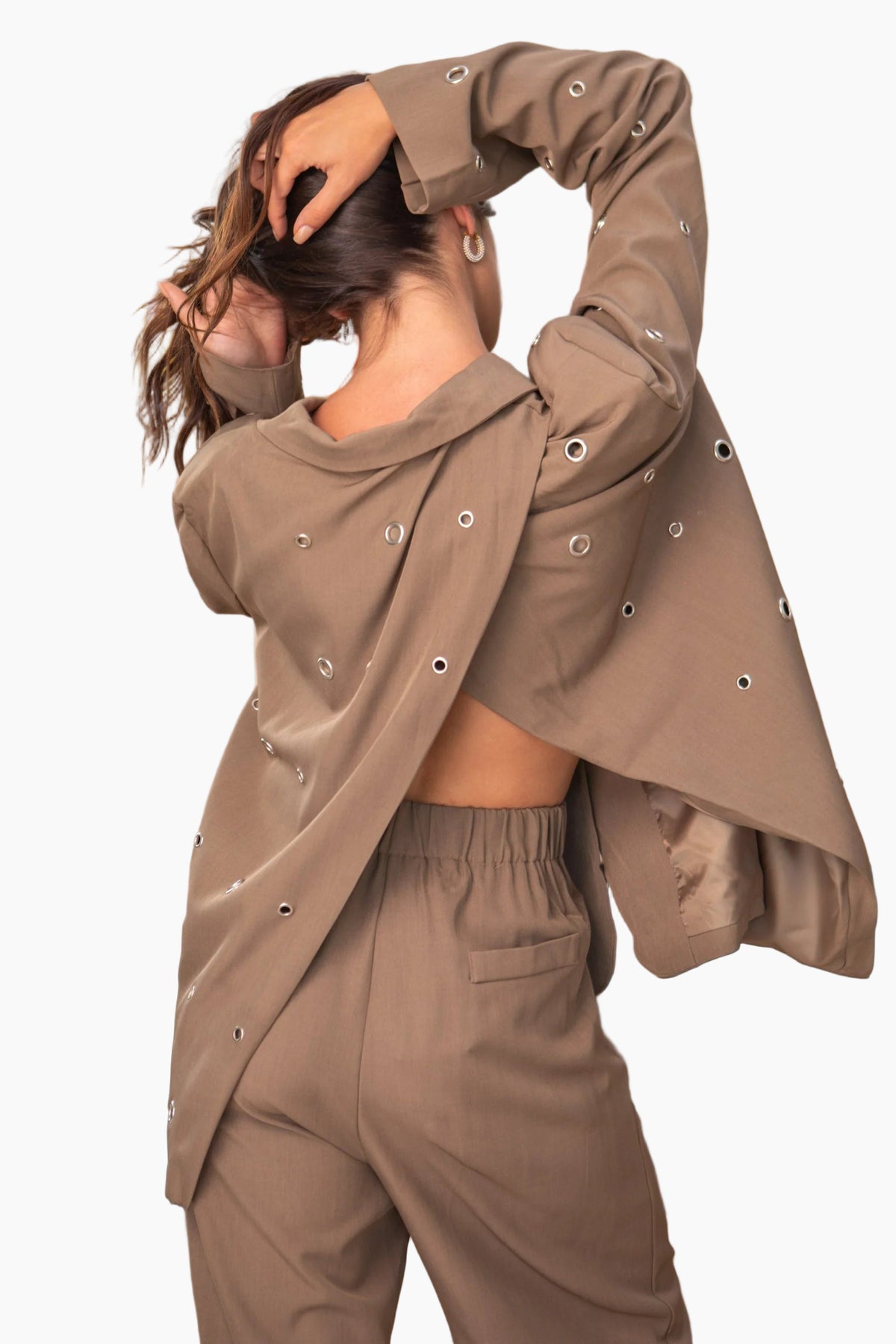 Person wearing a brown outfit with decorative buttons in a bathroom setting