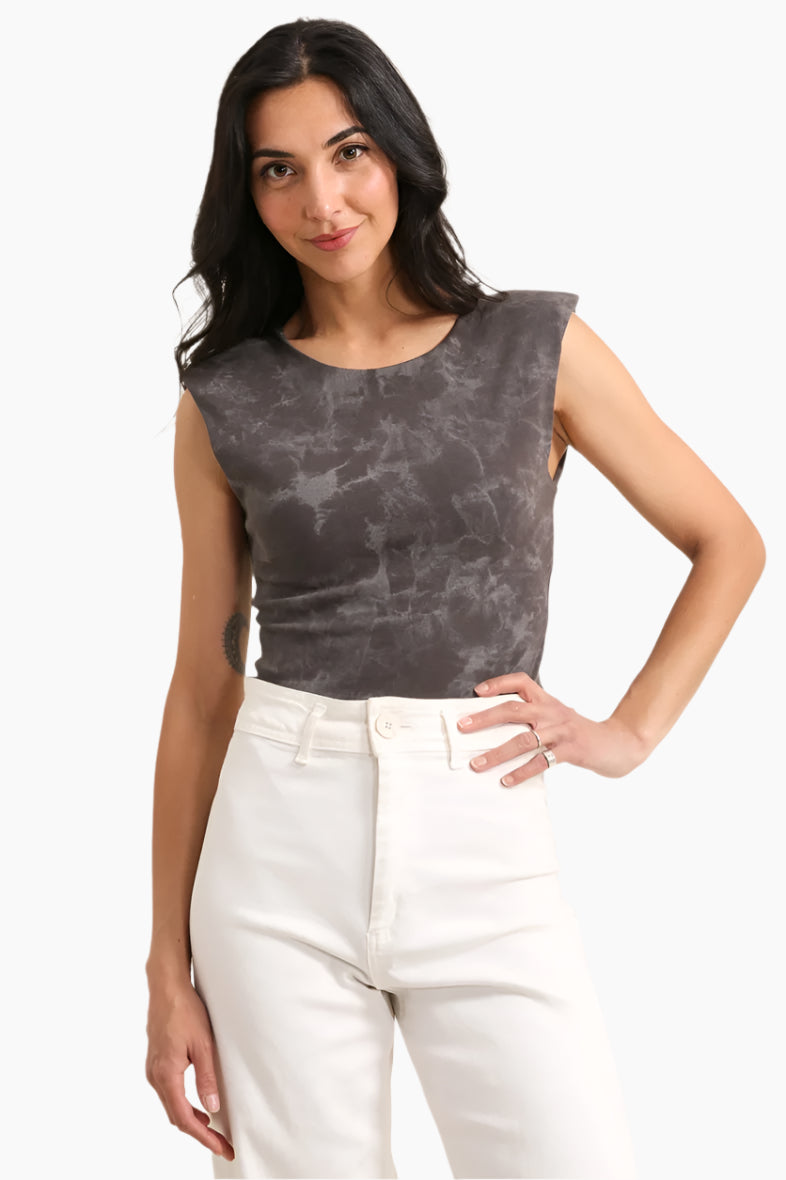 Woman wearing a gray sleeveless top and white pants