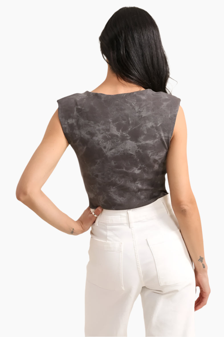 Woman wearing a sleeveless dark gray top and white pants