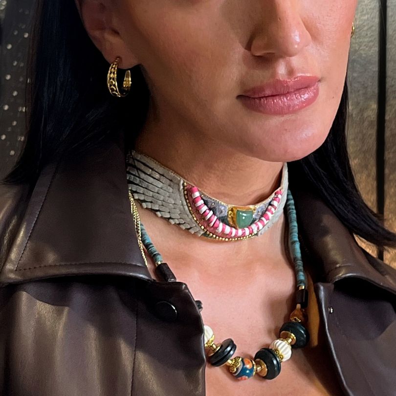 Close-up of a woman wearing multiple necklaces and hoop earrings.