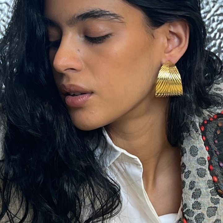 Close-up of a woman wearing gold triangle earrings