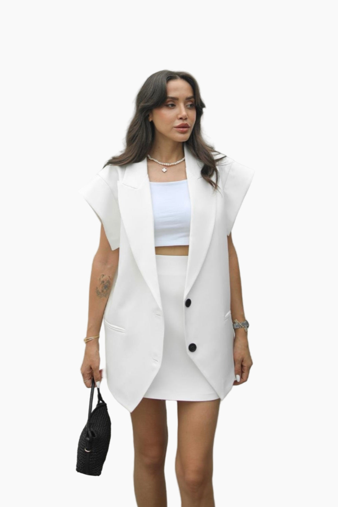 Woman wearing a white outfit with a vest against a plain background