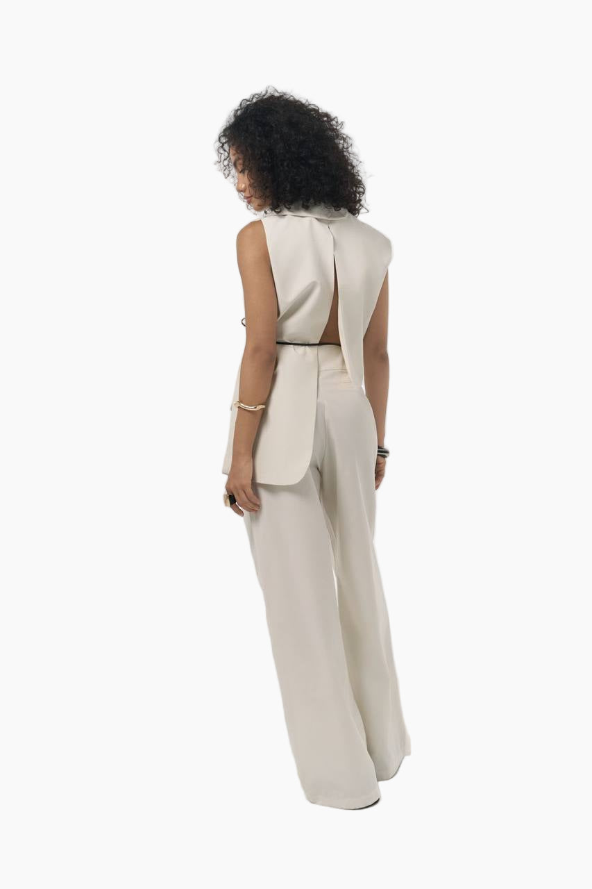 Woman wearing a beige outfit with a wide-leg pants and a matching jacket on a white background