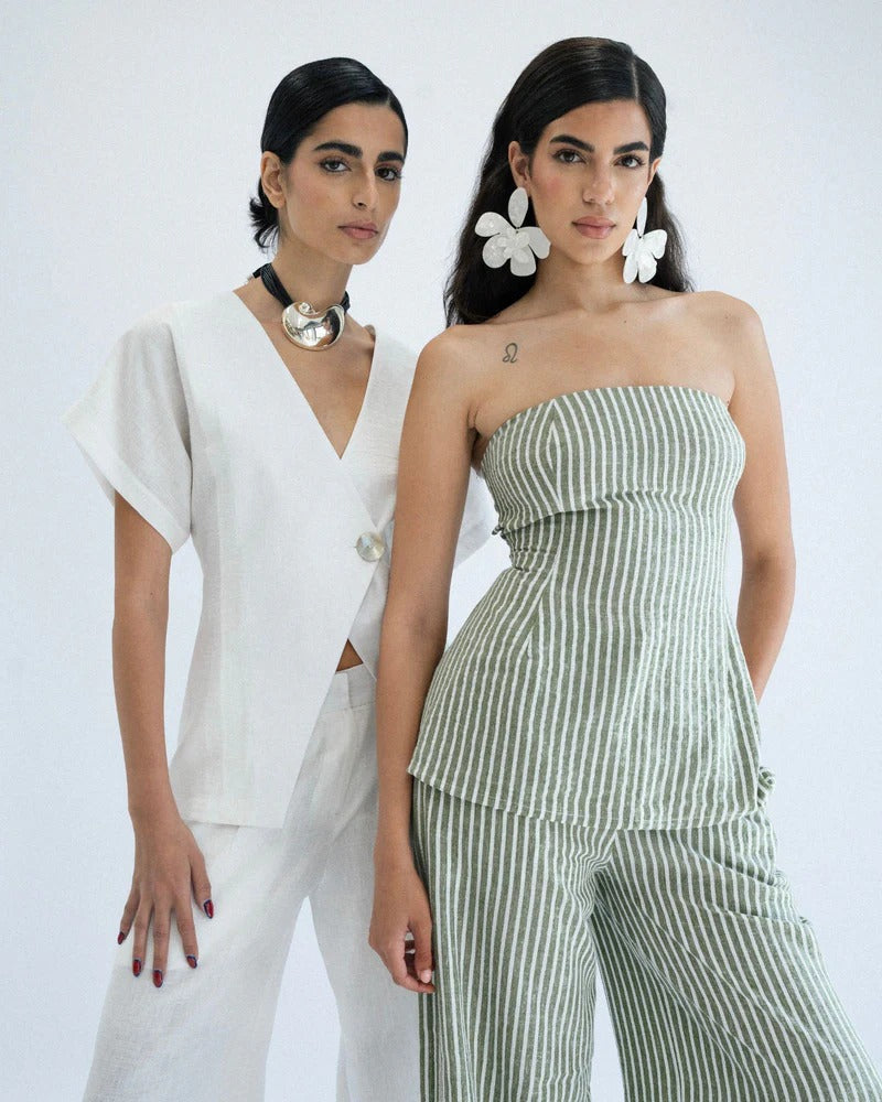 Two women, one in a white outfit and the other in a green striped outfit, standing side by side