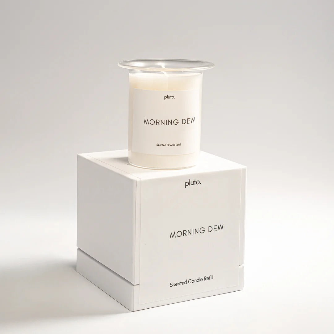 Candle labeled 'Morning Dew' by Pluto on a white box with the same label.