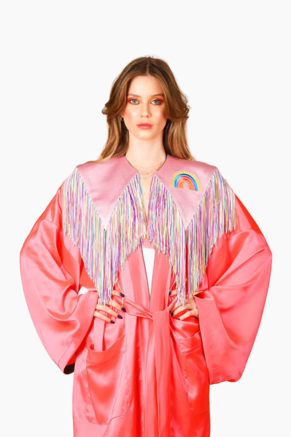 Person wearing a pink robe with rainbow decorations on a white background