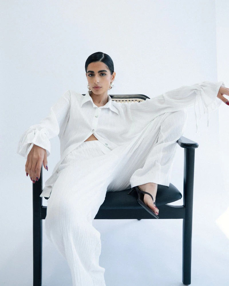 Person wearing a white outfit sitting on a black chair