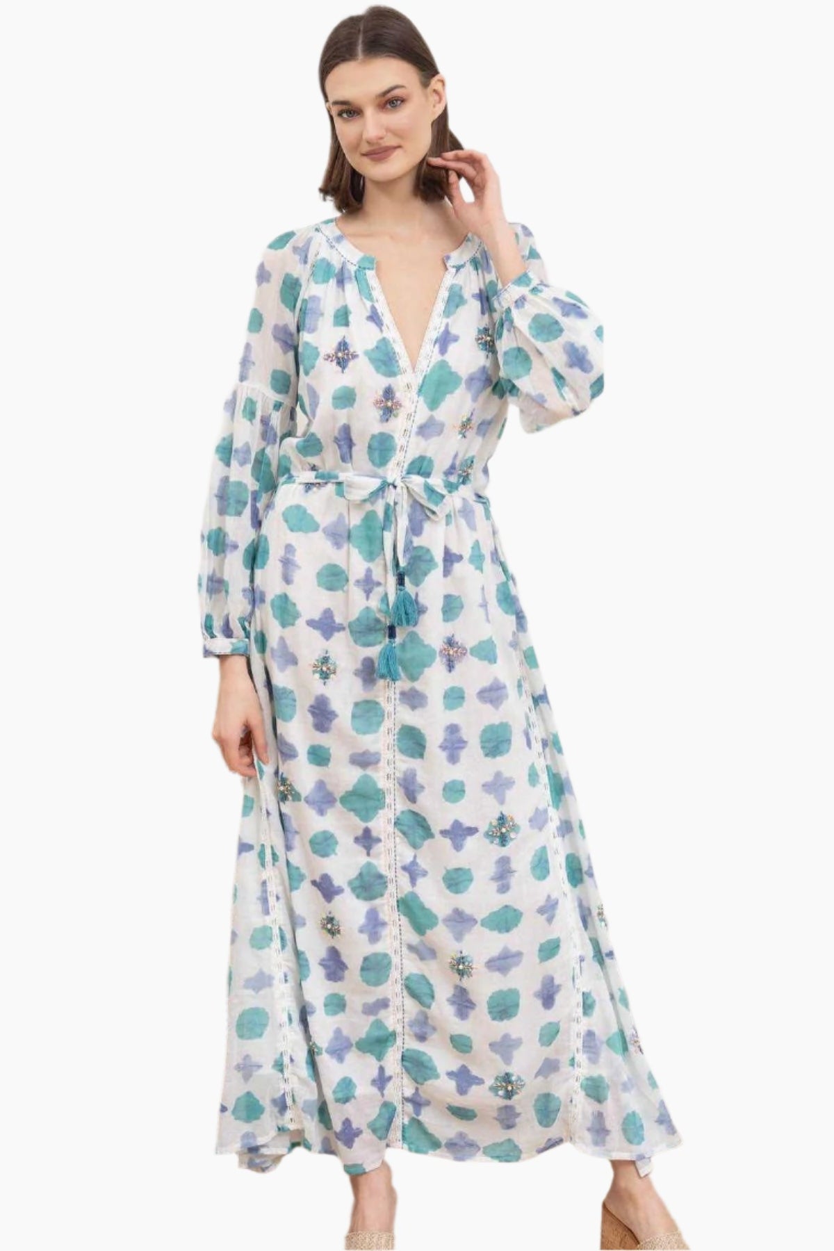 Woman wearing a floral white and blue dress with a tinny belt from the same fabric with tassels