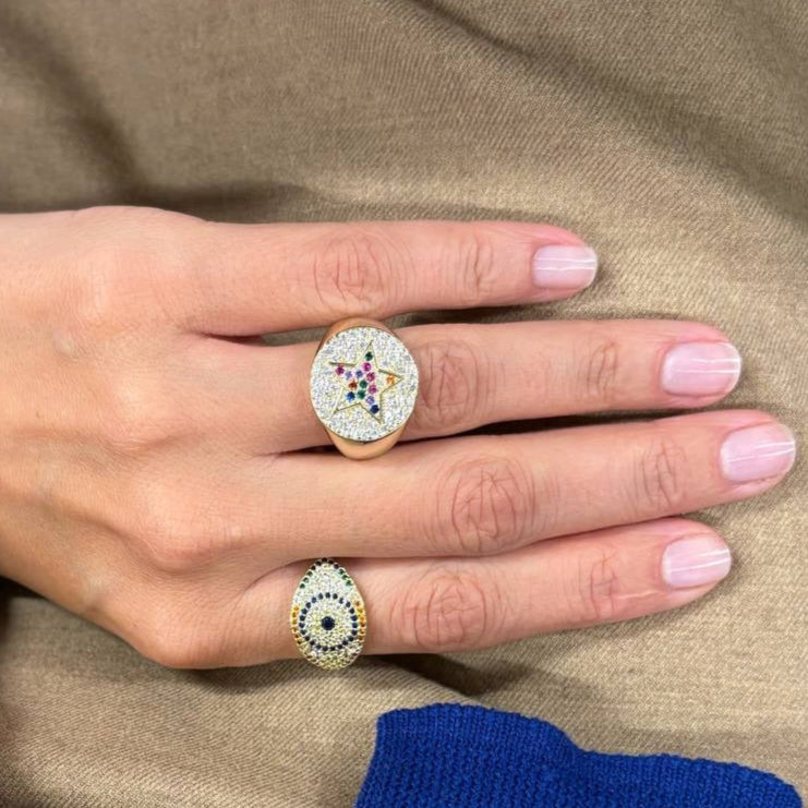 Close-up of a hand wearing two rings on a beige background