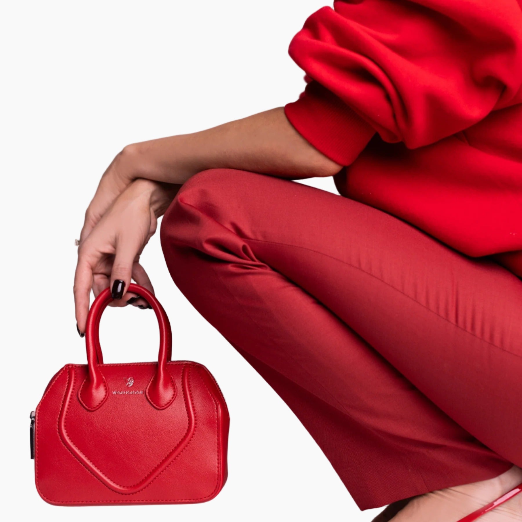Person wearing a red outfit holding a matching red handbag on a light background