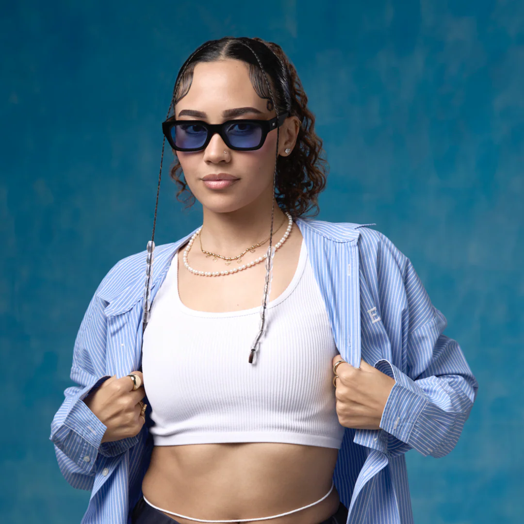 Woman wearing sunglasses and a blue shirt against a blue background
