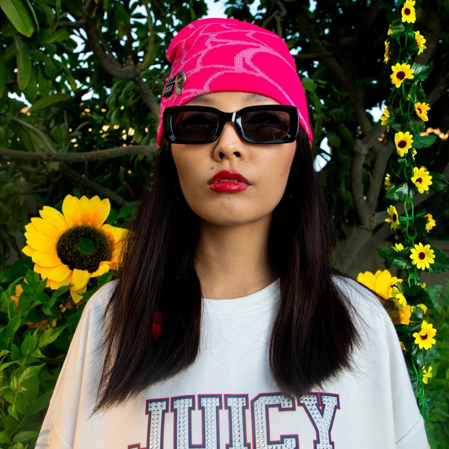 Person wearing a pink headband and a black sunglass with sunflowers in the background