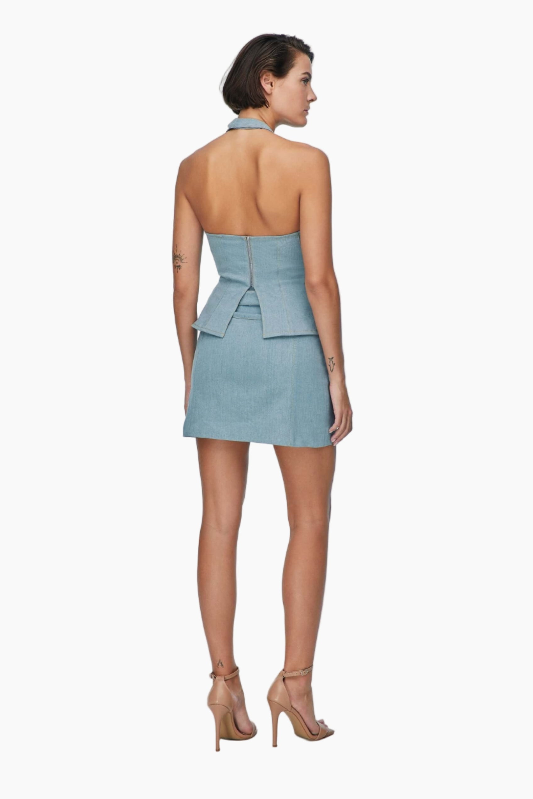 Woman wearing a light blue denim skirt with a halter top