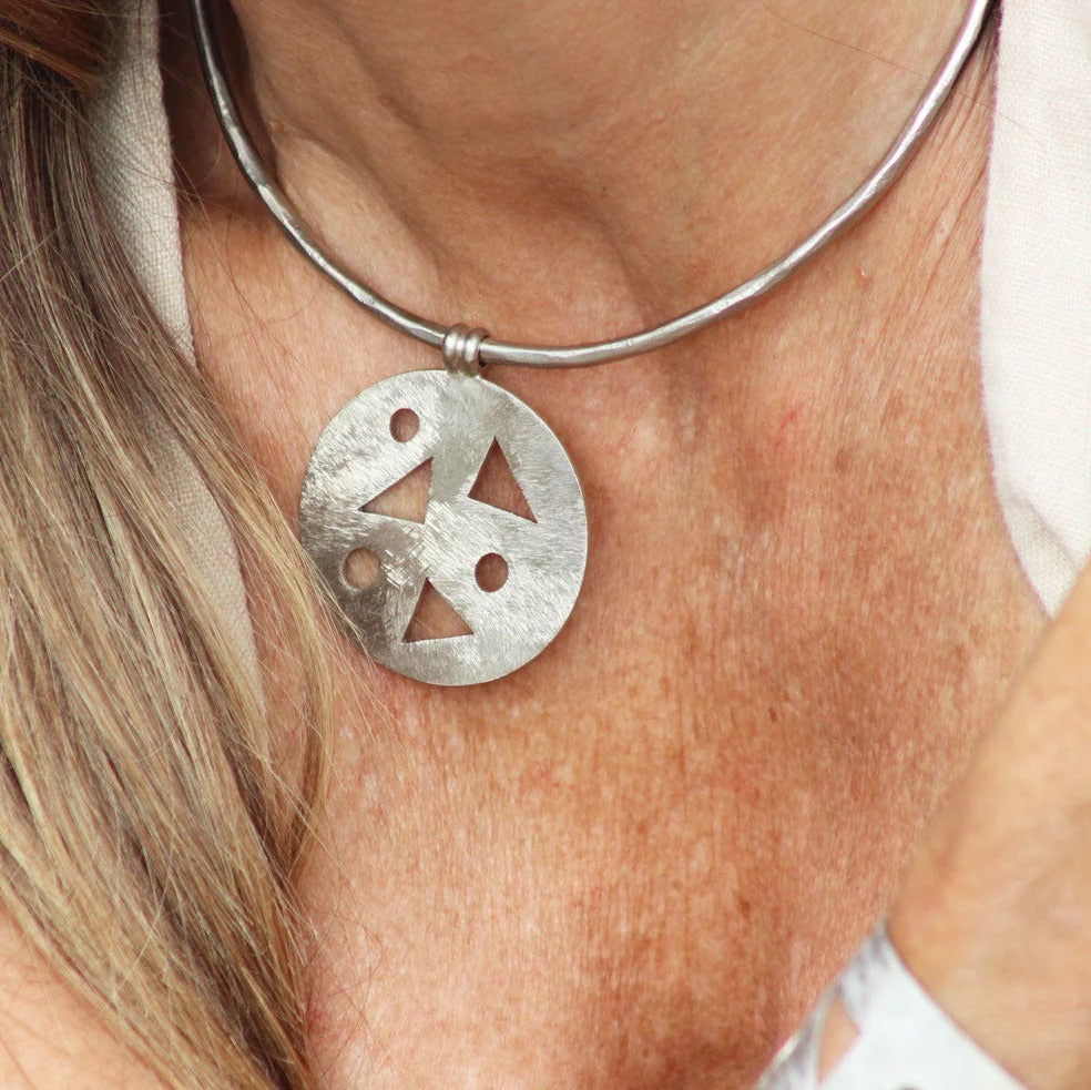 Close-up of a silver necklace with a unique pendant on a person's neck.
